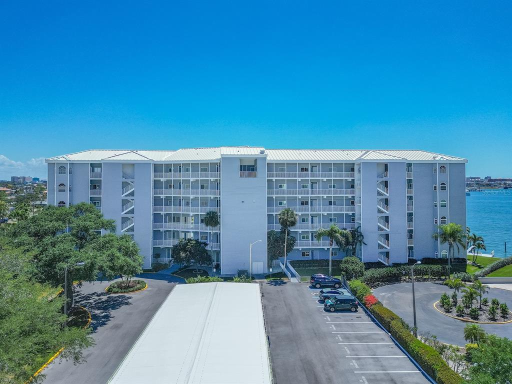 An aerial view of a multi-story apartment building with a parking lot and waterfront — 610 ISLAND WAY UNIT 407, CLEARWATER BEACH, FL