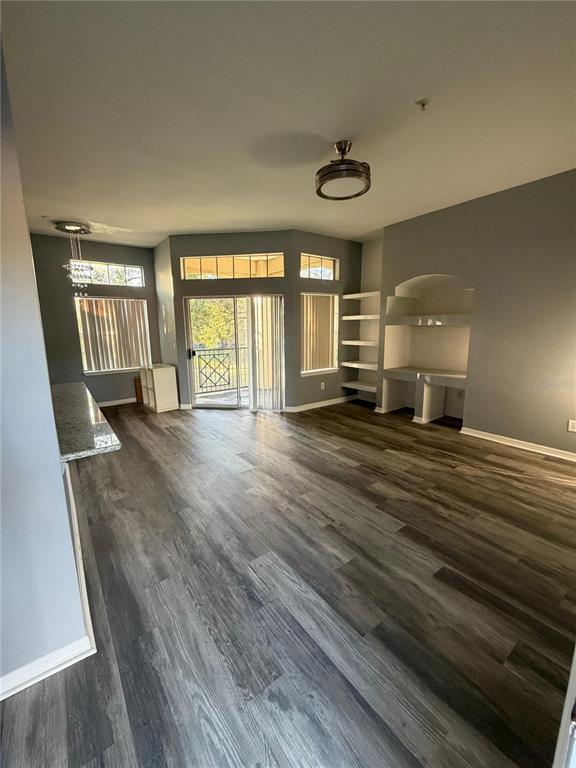An open living area features gray walls, wood-look flooring, a ceiling fan, and built-in shelving — 7250 WESTPOINTE BOULEVARD UNIT 1034, ORLANDO, FL