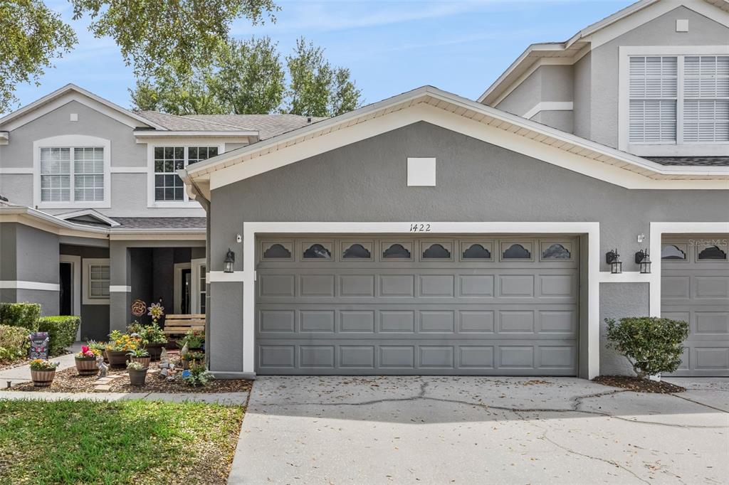 A gray two-story townhouse features a two-car garage and a small front garden area — 1422 TRAVERTINE TERRACE, SANFORD, FL