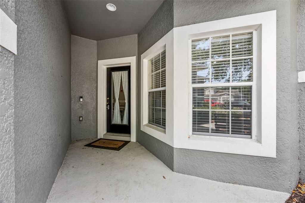 A covered entryway features a dark front door with curtains and a large bay window — 1422 TRAVERTINE TERRACE, SANFORD, FL