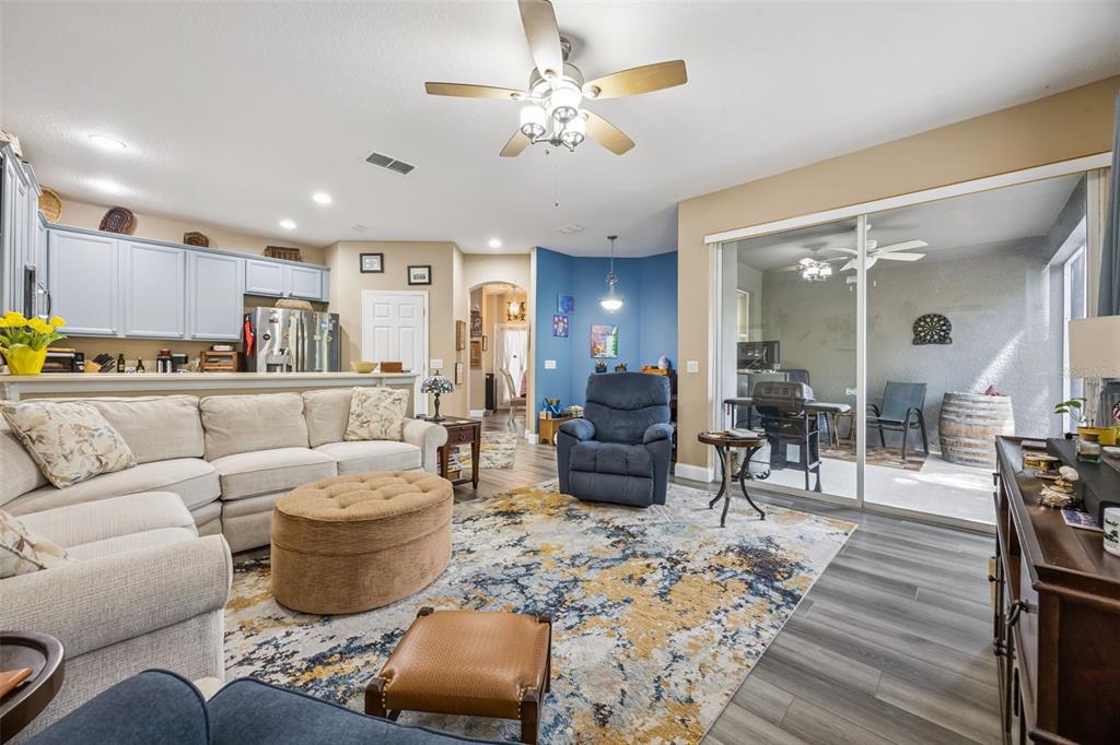 A living room with a sectional sofa, blue recliner, area rug, and sliding glass patio doors — 1422 TRAVERTINE TERRACE, SANFORD, FL