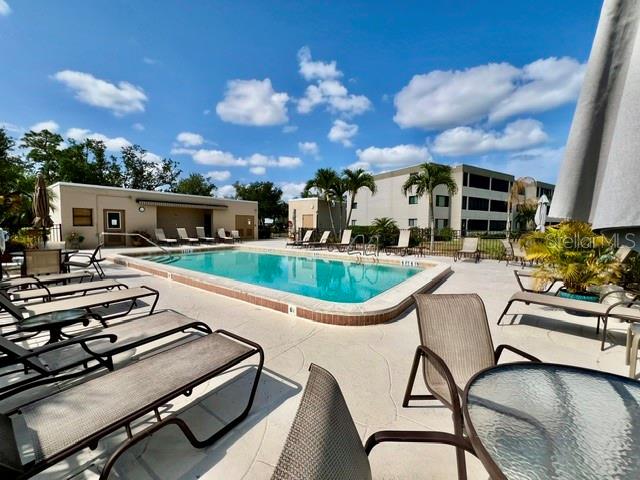 A swimming pool is surrounded by lounge chairs and a multi-story building under a blue sky — 801 ISLAMORADA BOULEVARD UNIT 25B, PUNTA GORDA, FL