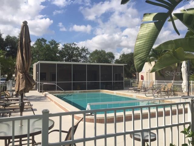 A rectangular swimming pool sits on a patio next to a screened-in building — 801 ISLAMORADA BOULEVARD UNIT 25B, PUNTA GORDA, FL