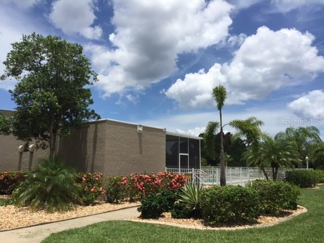 A tan building exterior features a screened-in patio area next to a swimming pool — 801 ISLAMORADA BOULEVARD UNIT 25B, PUNTA GORDA, FL