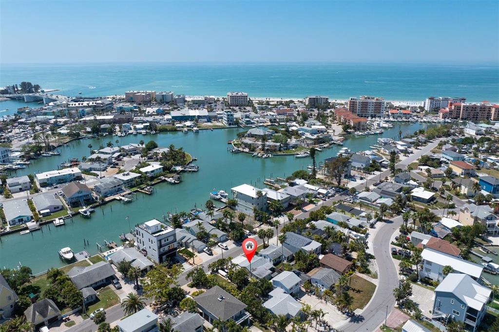 An aerial view shows a residential neighborhood with a canal and the ocean nearby — 358 BOCA CIEGA DRIVE, MADEIRA BEACH, FL