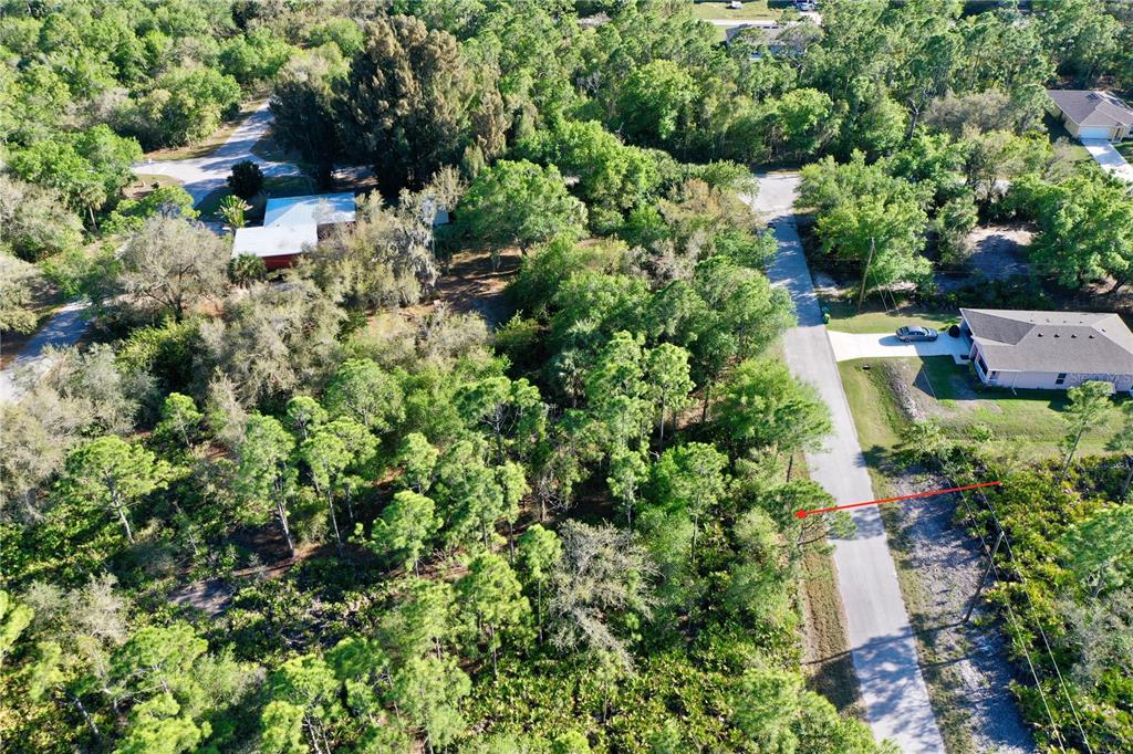 An aerial view shows a wooded lot adjacent to a paved road and nearby houses — 3310 SLATER STREET, PORT CHARLOTTE, FL