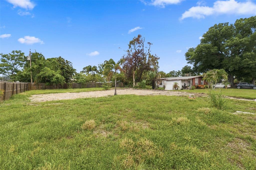 A large, grassy lot with a sandy area and a house in the background — 3963 NEPTUNE DRIVE SE, ST PETERSBURG, FL