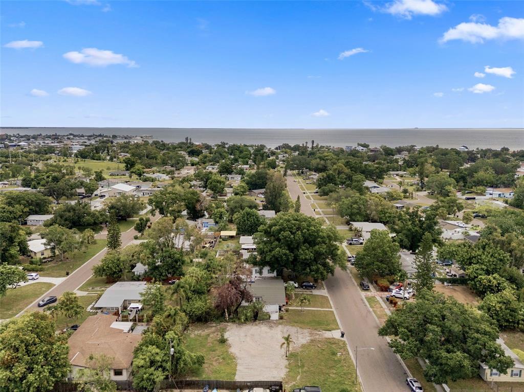 An aerial view shows a residential neighborhood with houses, trees, and a distant body of water — 3963 NEPTUNE DRIVE SE, ST PETERSBURG, FL