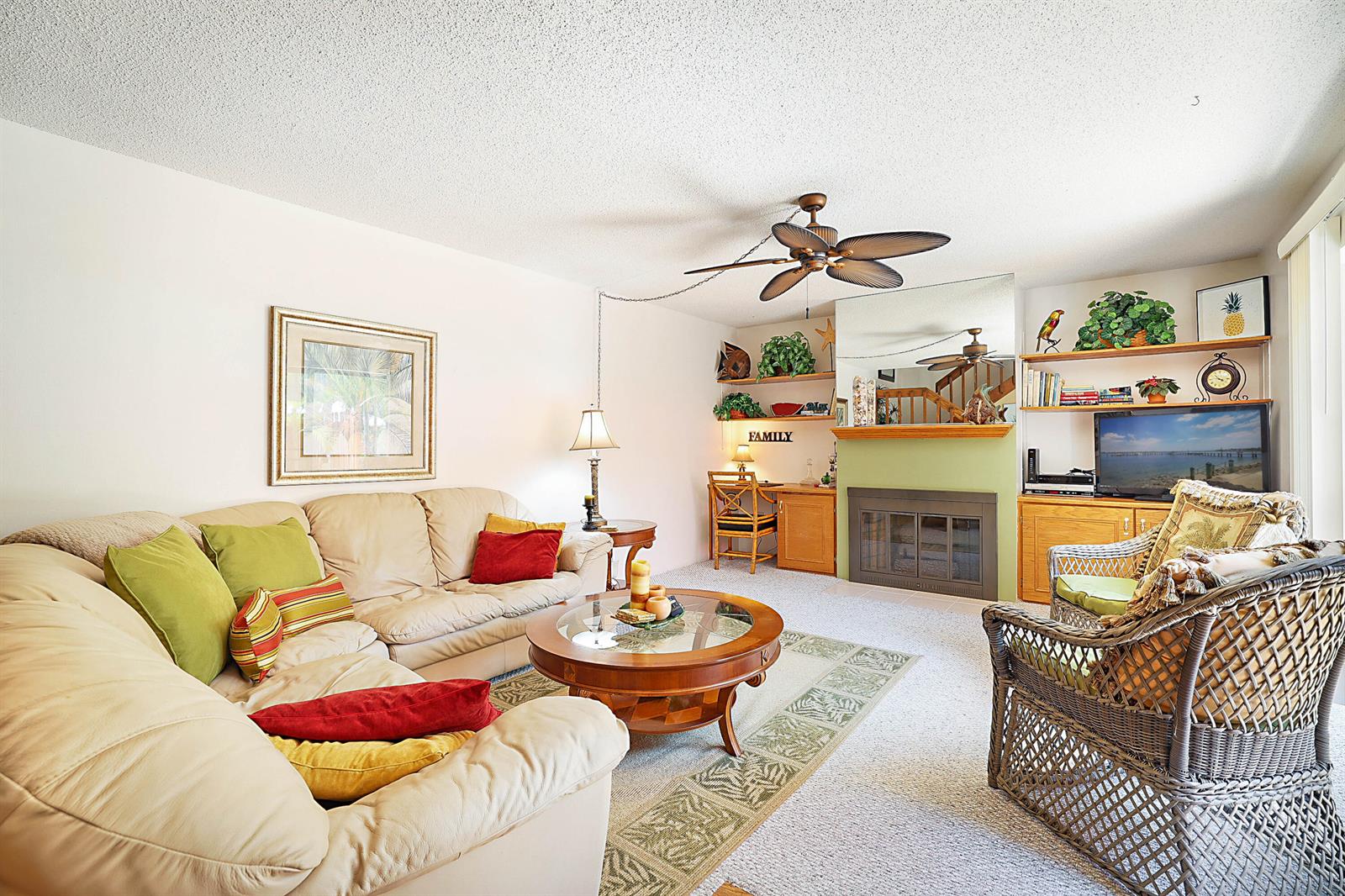 A living room features a beige sectional sofa, a fireplace, a television, and wicker furniture — 825 Center Street # 11c, Jupiter FL 33458, JUPITER, FL