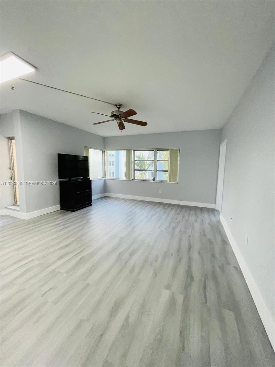 A living room features light gray walls, wood-look flooring, a ceiling fan, and corner windows — 9175 SW 77th Ave # 306, Miami FL 33156, MIAMI, FL