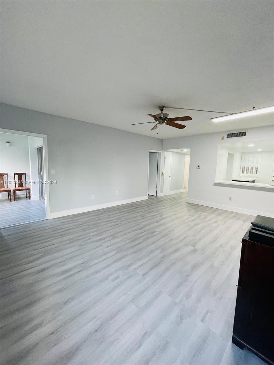 A living room features light gray wood-look flooring, a ceiling fan, and a kitchen pass-through — 9175 SW 77th Ave # 306, Miami FL 33156, MIAMI, FL