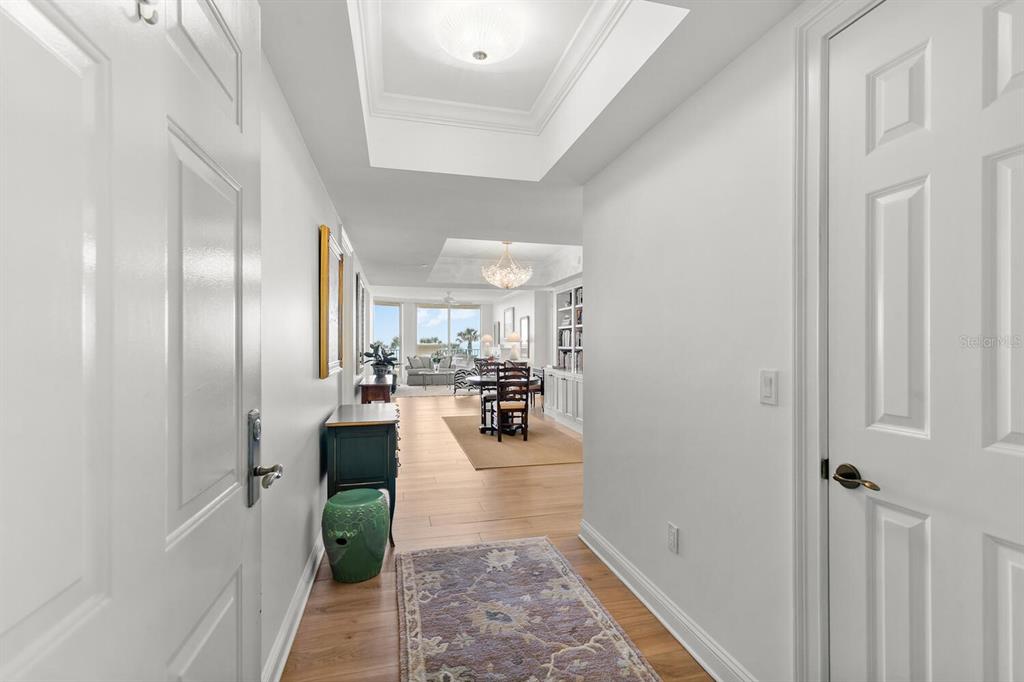 A view from an entryway looking down a hallway into a bright, open-concept living area — 20 PORTO MAR UNIT 202, PALM COAST, FL