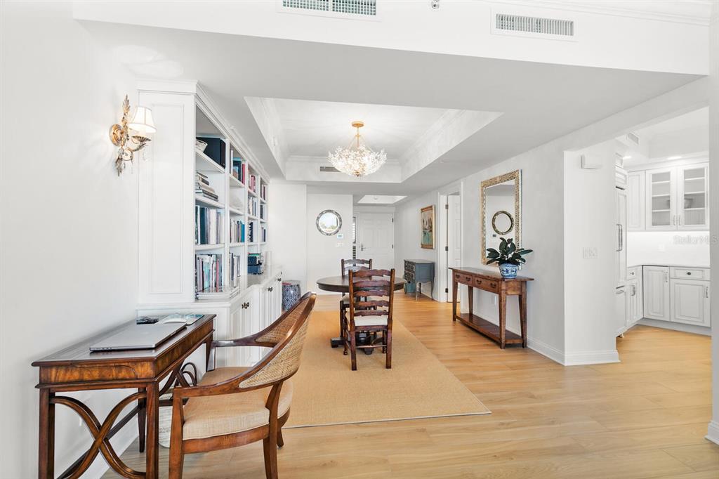 A bright room features a wooden desk, built-in bookshelves, a dining table, and light flooring — 20 PORTO MAR UNIT 202, PALM COAST, FL