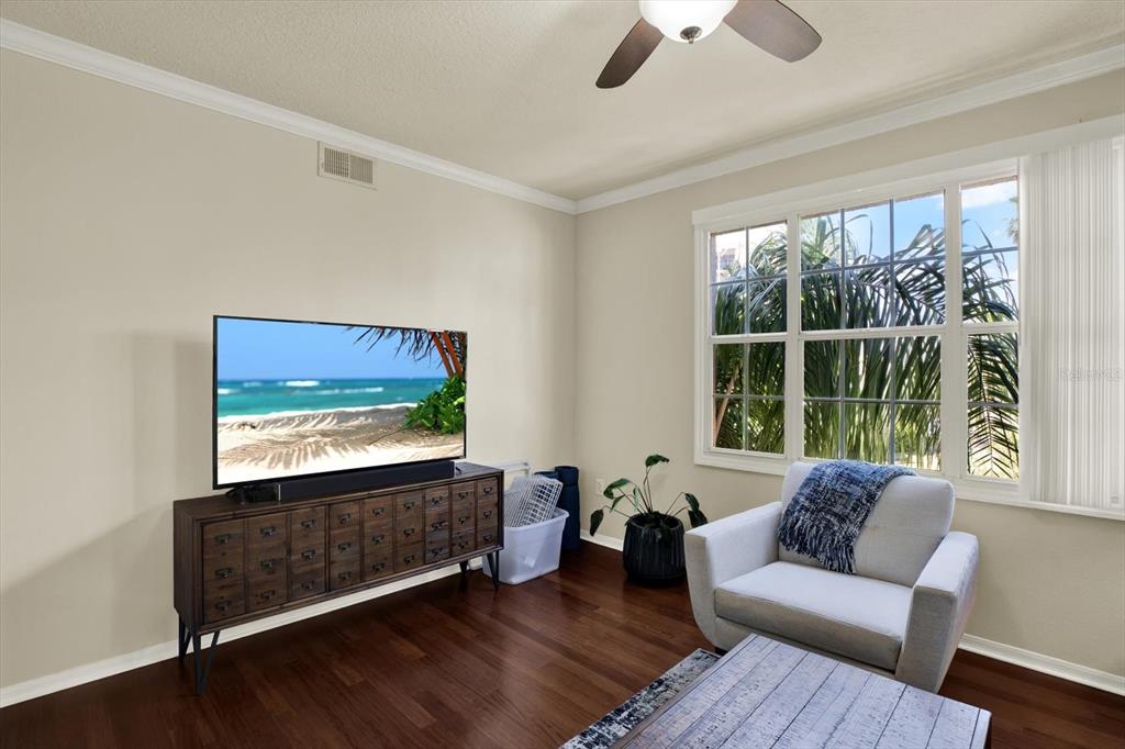 A living room features dark wood floors, a television on a console, and an armchair — 501 KNIGHTS RUN AVE UNIT 1234, TAMPA, FL