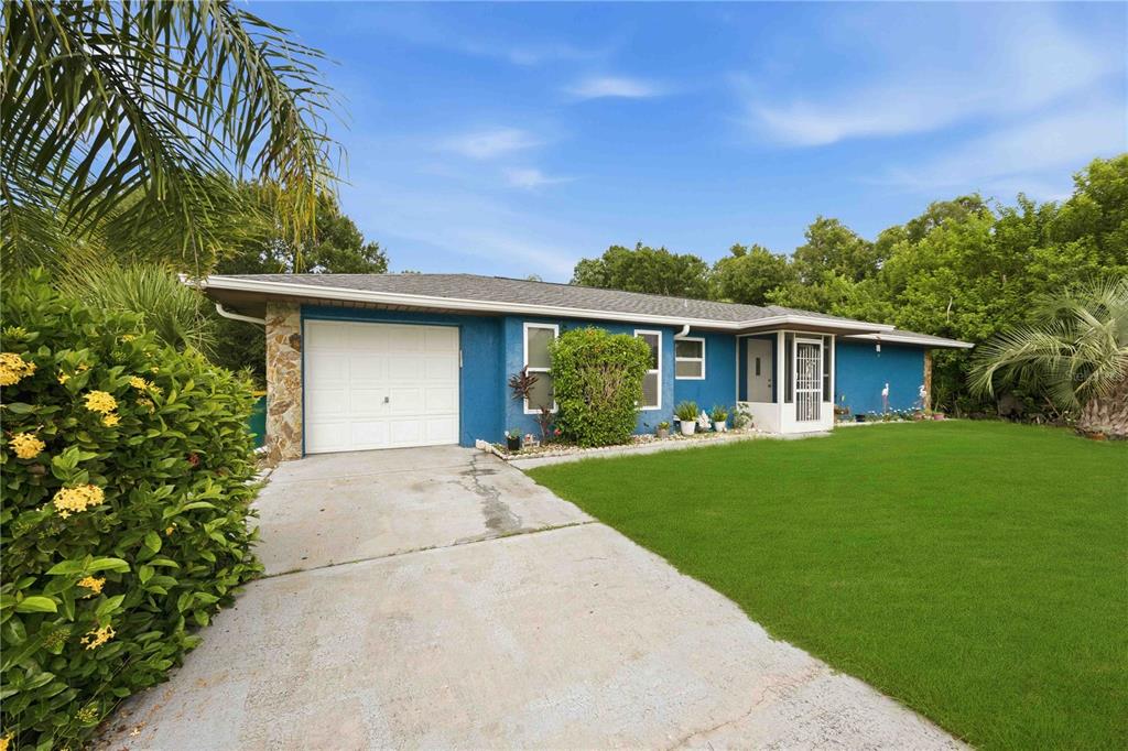 A blue single-story house with a white garage door and a concrete driveway — 22442 VALE AVENUE, PUNTA GORDA, FL