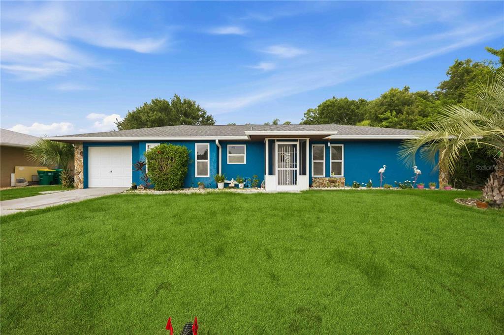 A single-story blue house with a white garage door and a front lawn — 22442 VALE AVENUE, PUNTA GORDA, FL