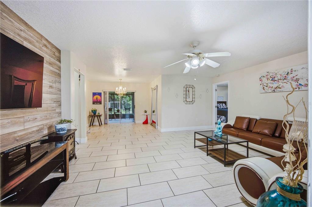 A living room features light tile flooring, a wood-paneled accent wall, and a brown sofa — 22442 VALE AVENUE, PUNTA GORDA, FL