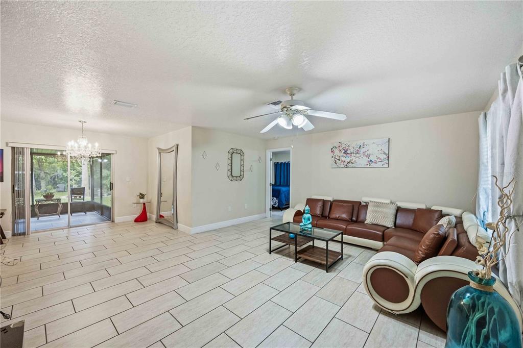 A living room features light tile floors, a brown sectional sofa, and a sliding glass door — 22442 VALE AVENUE, PUNTA GORDA, FL