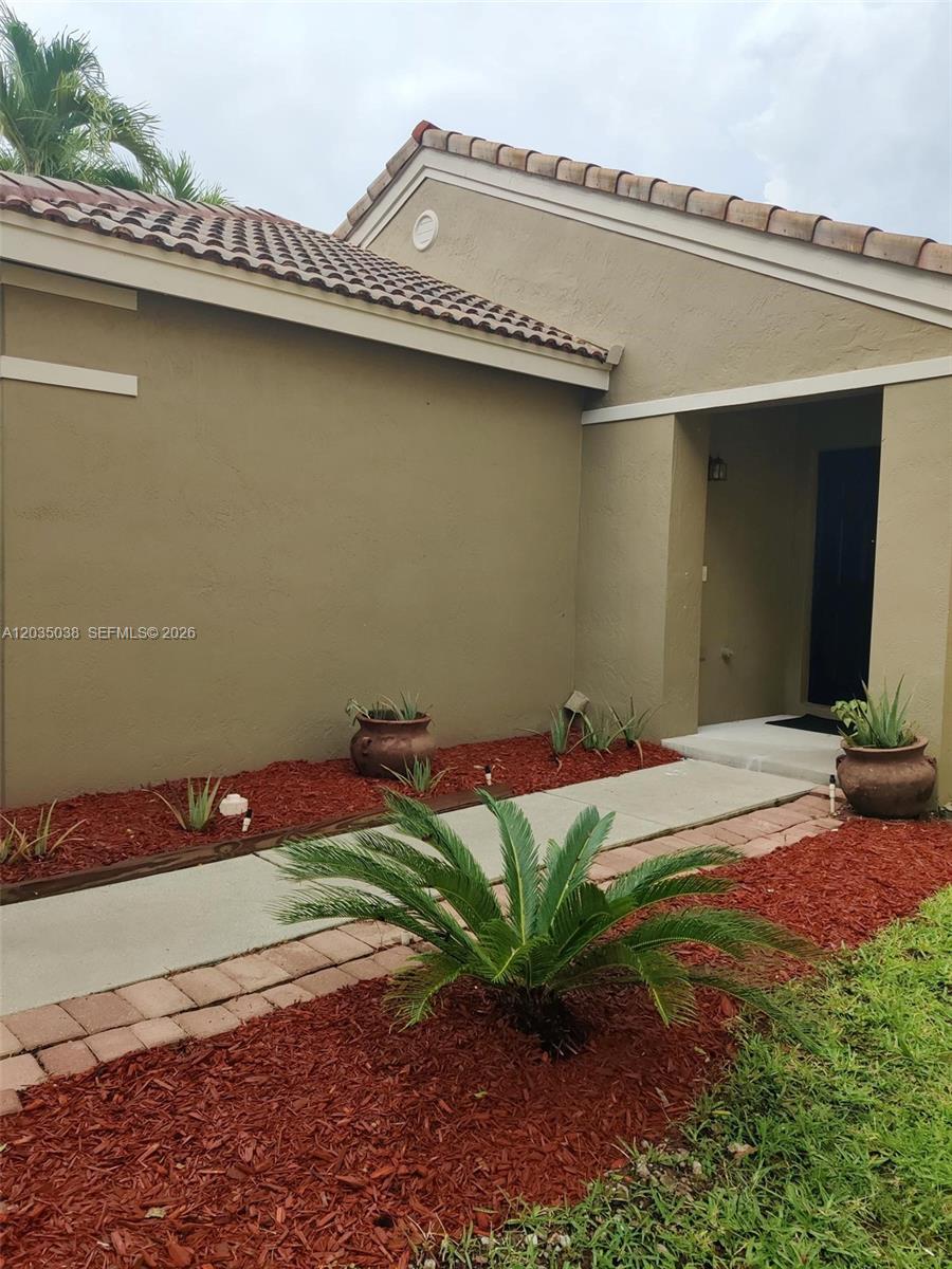 The exterior of a tan stucco house features a tiled roof and a walkway — 4315 Greenbriar Ln, Weston FL 33331, WESTON, FL