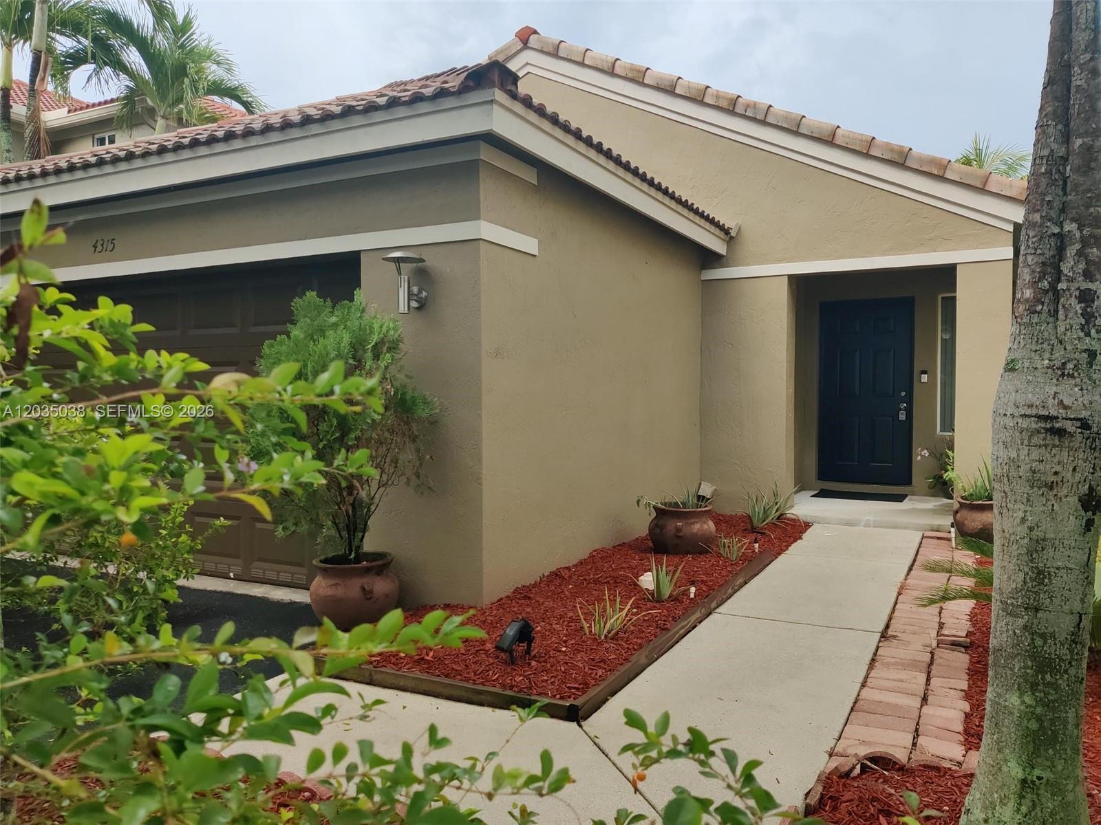 The exterior view shows a tan house with a brown garage door and front entrance — 4315 Greenbriar Ln, Weston FL 33331, WESTON, FL