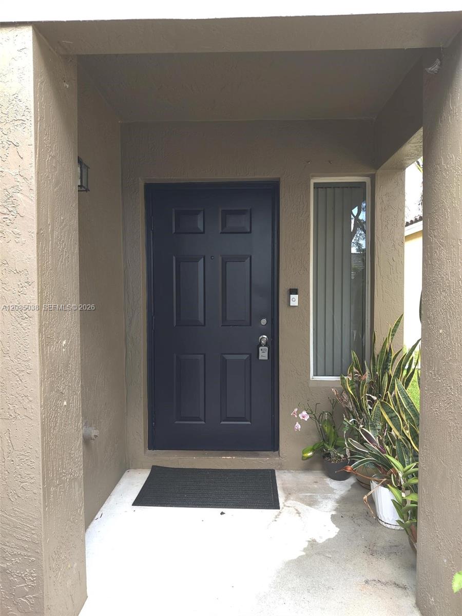 A dark blue front door with a side window sits under a covered entryway — 4315 Greenbriar Ln, Weston FL 33331, WESTON, FL