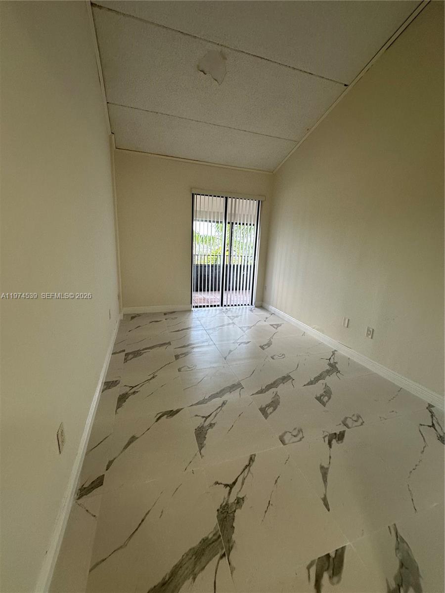 An empty room features white marble-patterned tile flooring, beige walls, and a sliding glass door — 16220 NW 2nd Ave # 512, Miami FL 33169, MIAMI, FL
