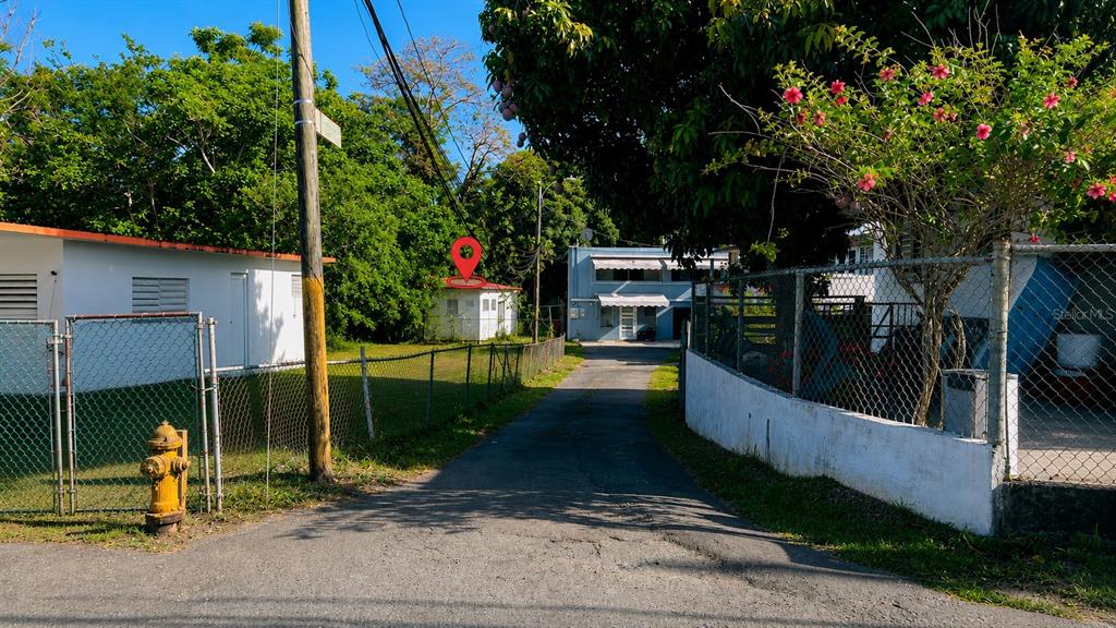 A paved driveway leads toward a small white house with a red roof — CO Villa Caridad AMPARO ST. UNIT D-10, CAROLINA, PR