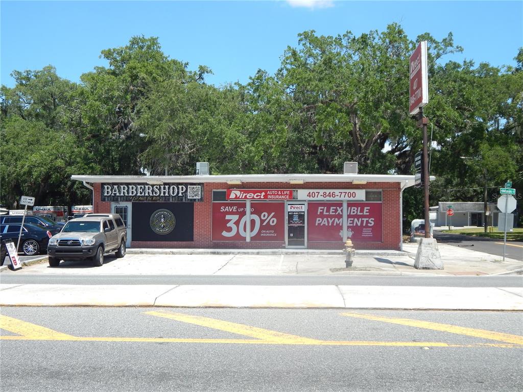 A single-story brick commercial building features a barbershop and an insurance office with parking — 1503 N MAIN STREET, KISSIMMEE, FL