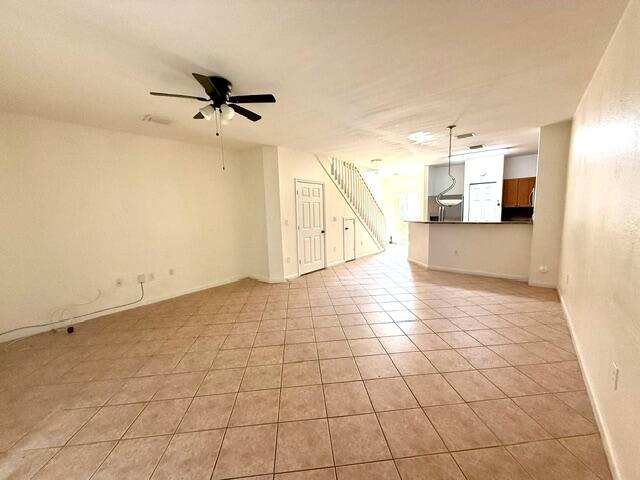 An open-concept living area features tile flooring, a ceiling fan, and a staircase — 460 Princess Drive, Margate FL 33068, MARGATE, FL