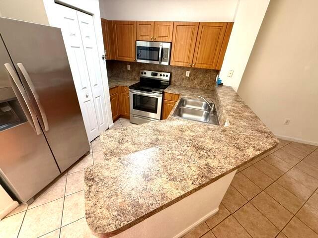 A kitchen features wood cabinets, a stainless steel refrigerator, and a laminate countertop peninsula — 460 Princess Drive, Margate FL 33068, MARGATE, FL