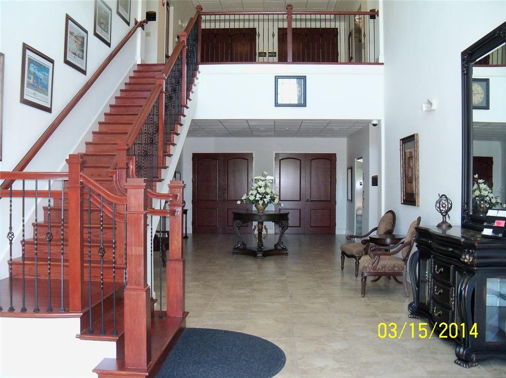 A grand foyer features a wooden staircase, tile flooring, and double doors leading to rooms — 2461 W STATE ROAD 426 UNIT 1021, OVIEDO, FL