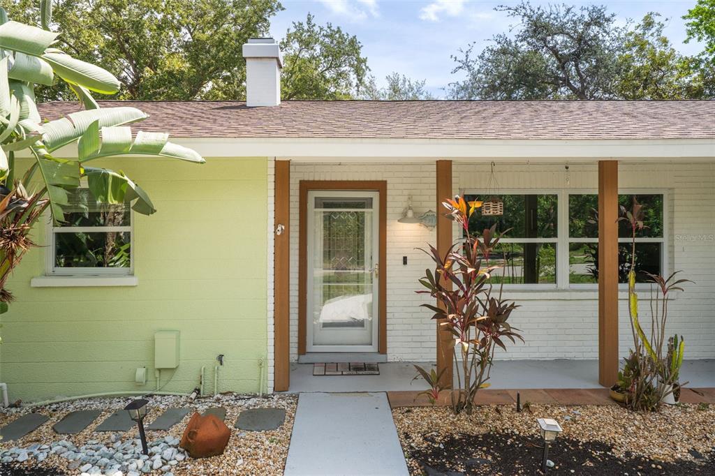 The exterior of a house features a light green wall, white brick, and wooden posts — 7311 BROUGHTON STREET, SARASOTA, FL