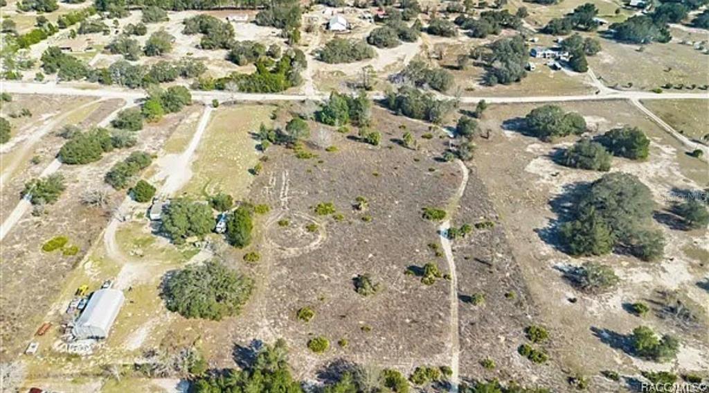 An aerial view shows a large, mostly cleared plot of land with scattered trees and structures — 6292 GEORGIAN RD, HOMOSASSA, FL