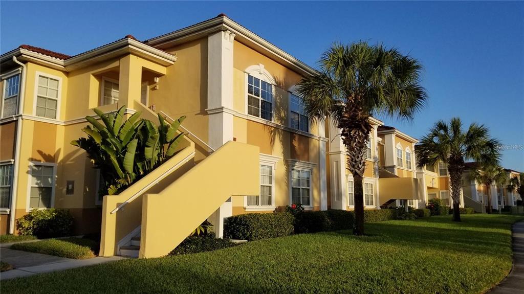 A two-story apartment building exterior at sunset with a palm tree and outdoor staircase — 1040 VILLAGIO CIRCLE UNIT 201, SARASOTA, FL