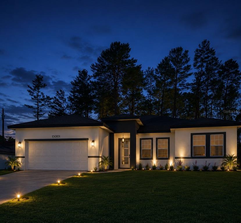 A modern single-story house with a white exterior, dark trim, and illuminated landscaping at dusk — 15001 SW 46TH CIR, OCALA, FL