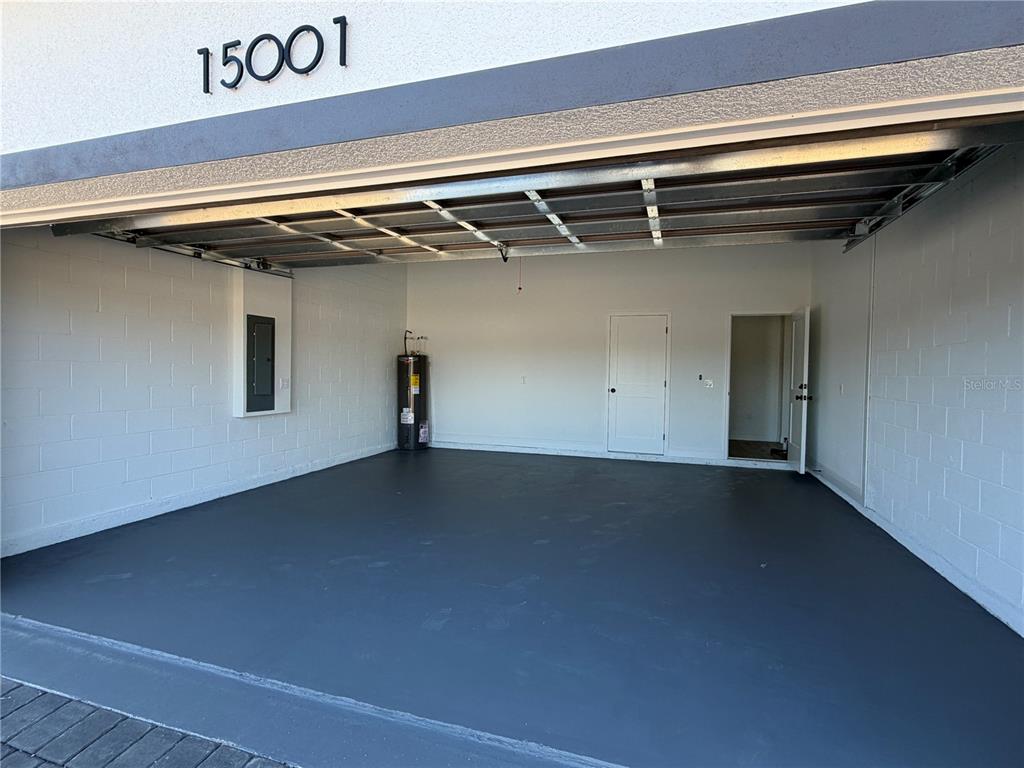 A garage with a painted concrete floor, a water heater, and two interior doors — 15001 SW 46TH CIR, OCALA, FL