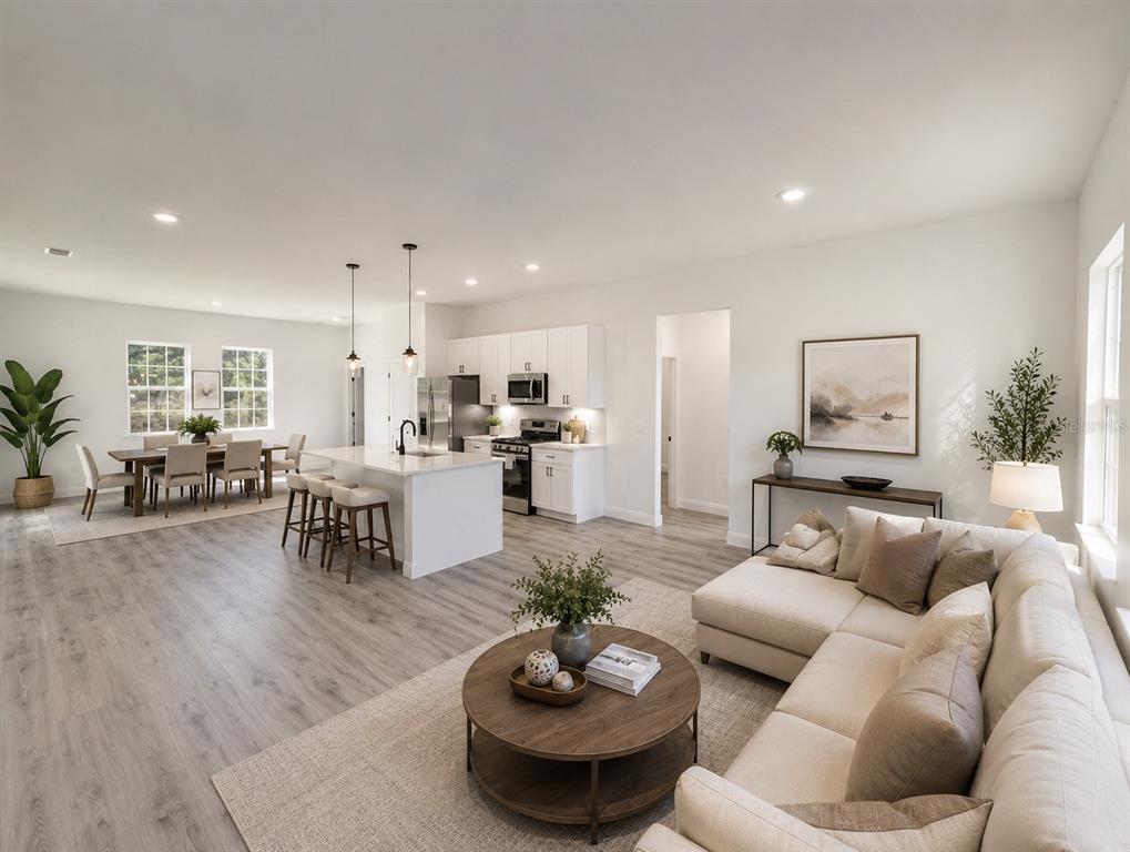 An open-concept living area features a kitchen with white cabinetry, a dining space, and seating — 15001 SW 46TH CIR, OCALA, FL