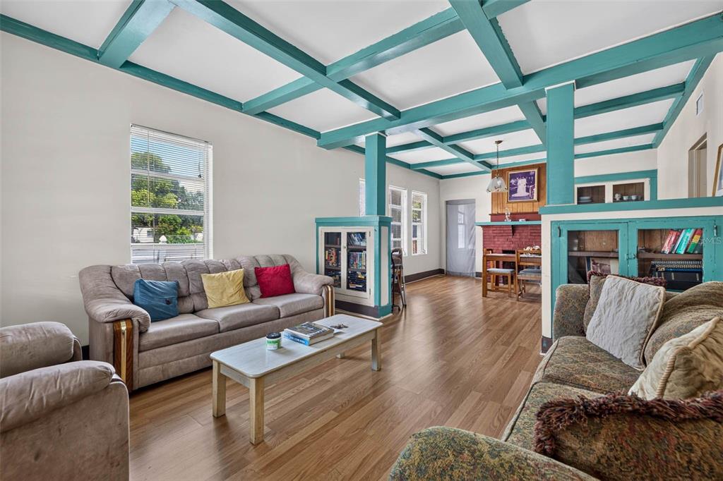 A living room features teal-painted ceiling beams, wood-look flooring, and a brick fireplace — 104 W 26TH AVENUE, TAMPA, FL