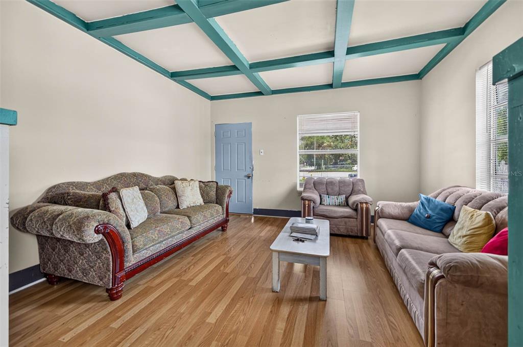 A living room features wood-look flooring, a coffered ceiling with teal beams, and three sofas — 104 W 26TH AVENUE, TAMPA, FL