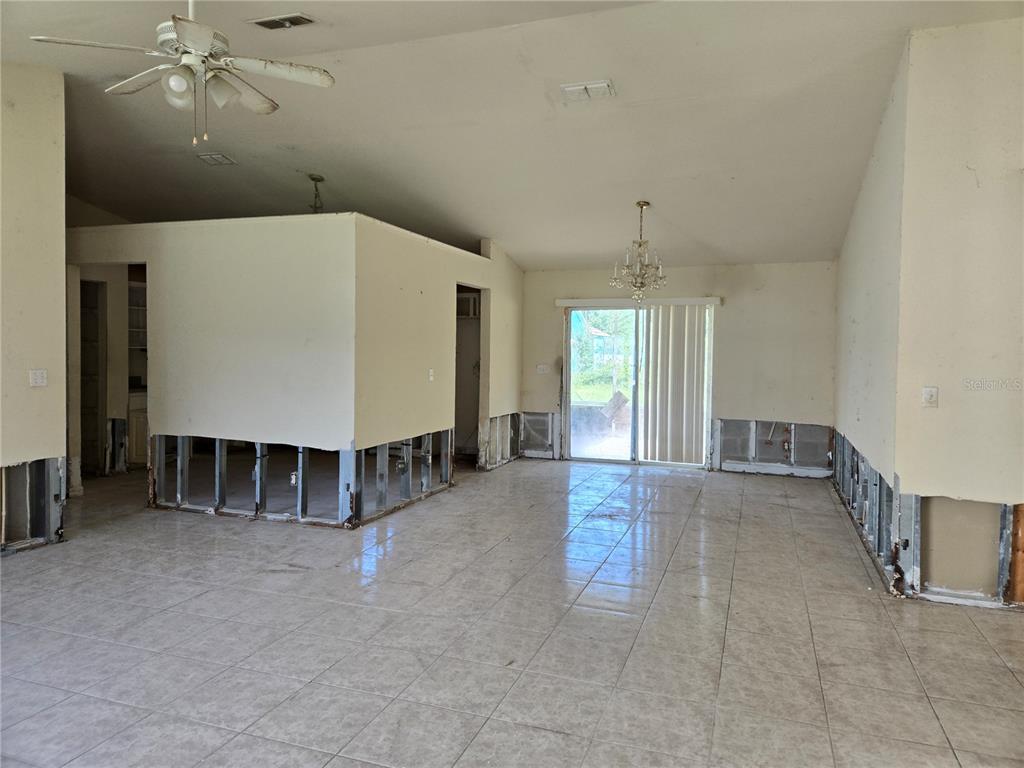 A living area with tile flooring and walls stripped to the studs for renovation — 1794 SW 161ST PLACE, OCALA, FL