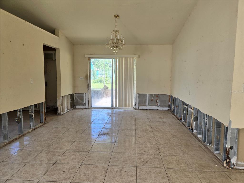 An unfinished room with exposed wall studs, tile flooring, and a sliding glass door — 1794 SW 161ST PLACE, OCALA, FL