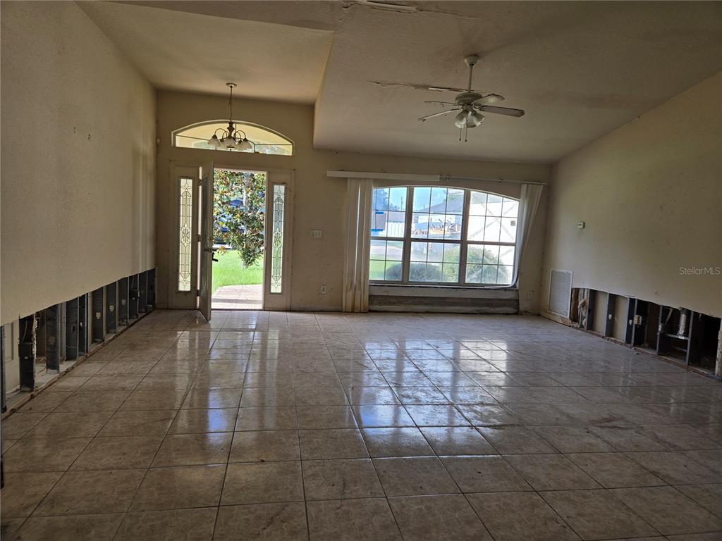 An unfinished living room features tile flooring, exposed wall studs, and a large arched window — 1794 SW 161ST PLACE, OCALA, FL
