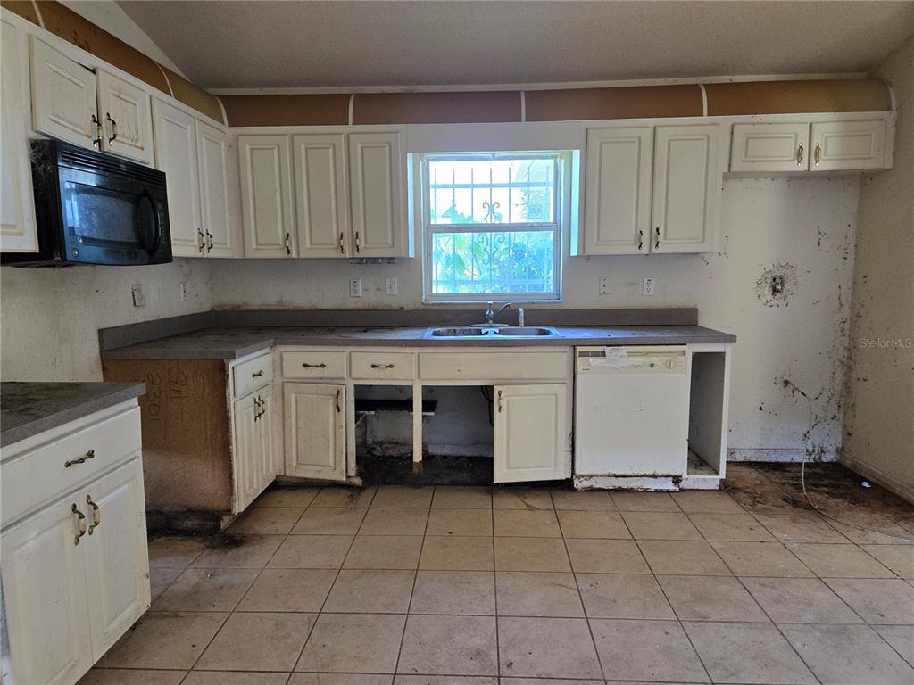 A kitchen with white cabinets, a window, a dishwasher, and missing lower cabinet doors — 1794 SW 161ST PLACE, OCALA, FL