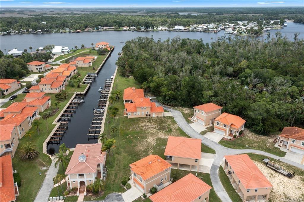 An aerial view shows a waterfront residential community with orange-roofed houses and a private canal — 4794 S POLDERLAND WAY, HOMOSASSA, FL