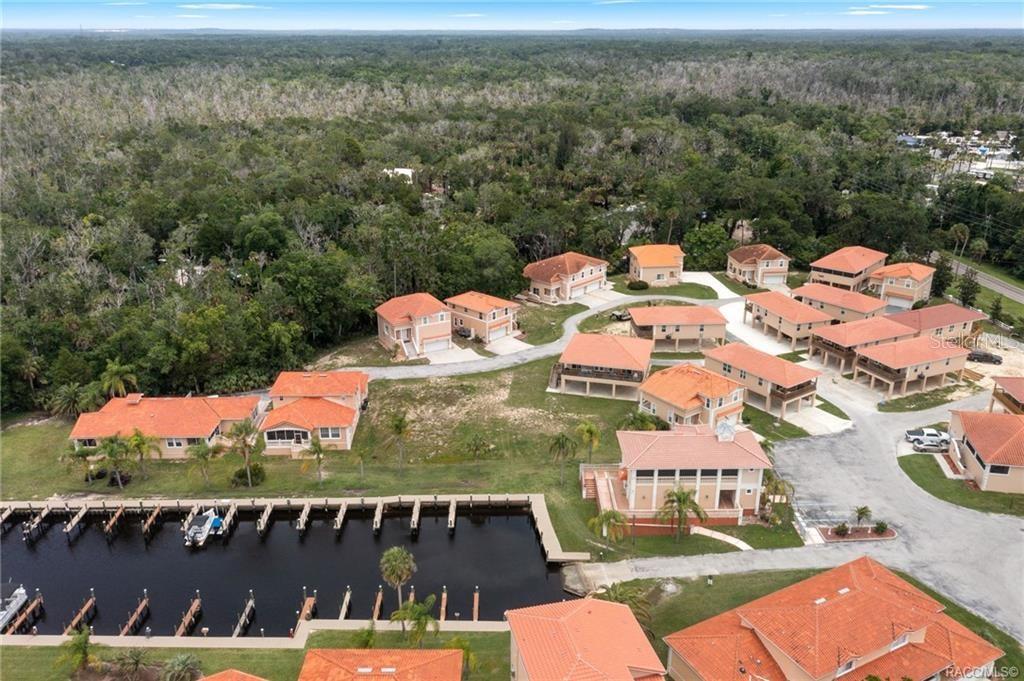 An aerial view shows a waterfront residential community with houses, a marina, and surrounding woods — 4794 S POLDERLAND WAY, HOMOSASSA, FL