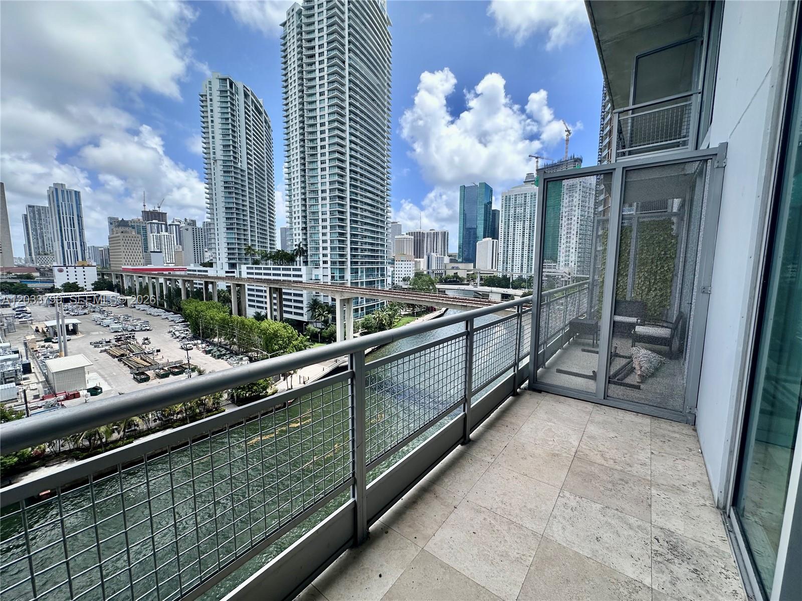 A balcony with a metal railing overlooks a river, a train track, and city skyscrapers — 690 SW 1st Ct # 1213, Miami FL 33130, MIAMI, FL
