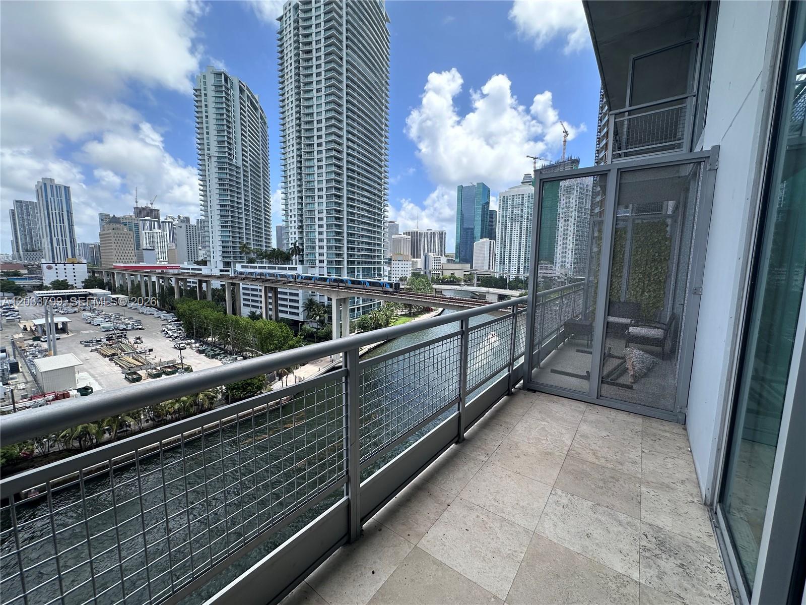 A balcony with a metal railing overlooks a canal, a train track, and city skyscrapers — 690 SW 1st Ct # 1213, Miami FL 33130, MIAMI, FL