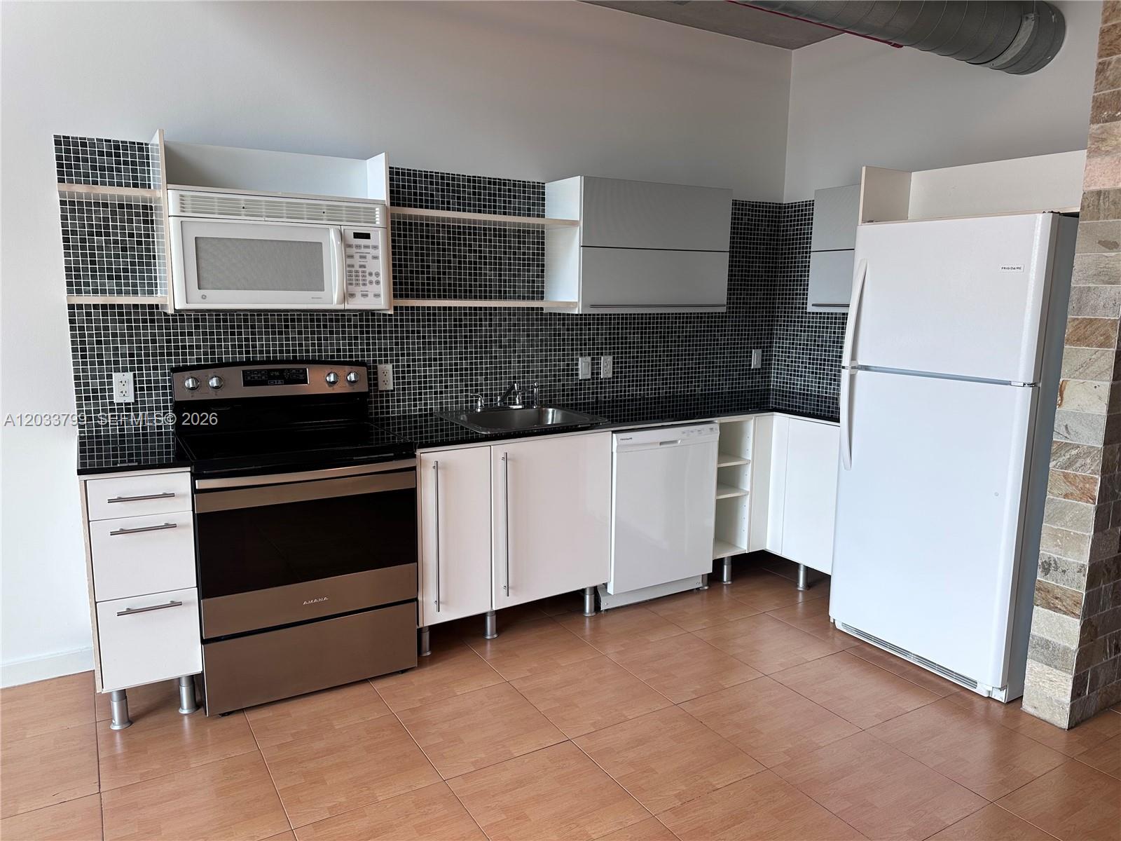 A kitchen features white cabinets, stainless steel appliances, and a black tiled backsplash — 690 SW 1st Ct # 1213, Miami FL 33130, MIAMI, FL