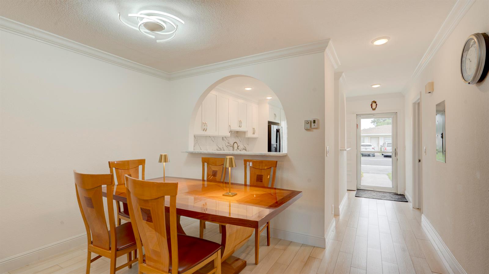 A dining room with a wooden table and chairs sits before an arched kitchen opening — 8638 Bella Vista Drive, Boca Raton FL 33433, BOCA RATON, FL