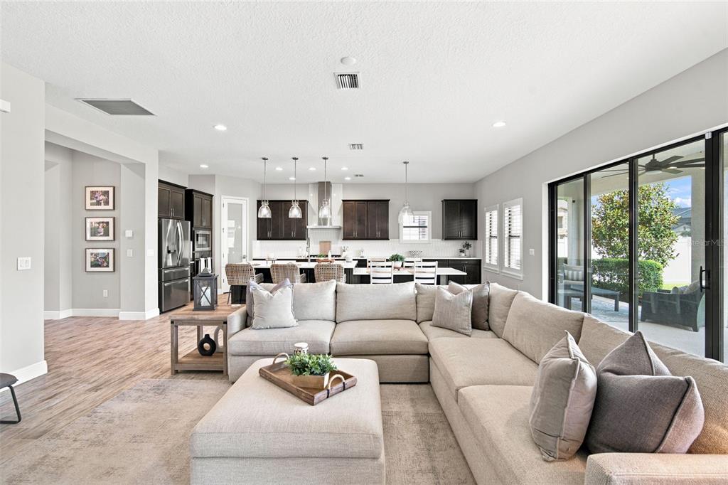 A spacious open-concept living room and kitchen featuring neutral tones and large sliding glass doors — 4587 SHORELEAF LOOP, VALRICO, FL